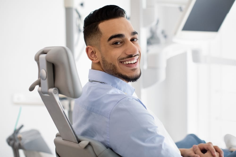 A man sits in a dental chair, smiling confidently during his orthodontic visit. - Orthodontics